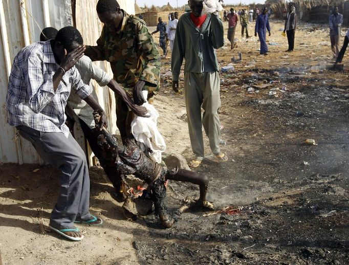 Men remove the burnt body of boy killed in an air strike by the Sudanese air force in a market in Rubkona