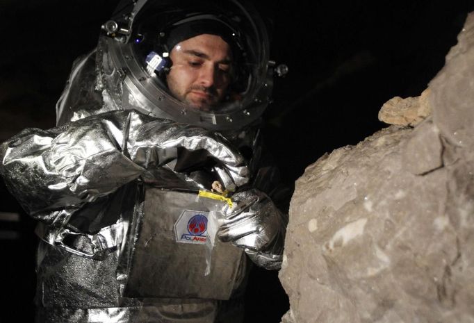 Physicist Daniel Schildhammer takes a rock sample as he wears the Aouda.X spacesuit simulator during a field test of Oesterreichisches Weltraum Forum (Austrian space forum) inside the Eisriesenhoehle (giant ice cave) at Dachstein mountain near the village of Obertraun April 28, 2012. Scientists were out of this world on Tuesday about tests in icy Alpine caves of the technology needed for a mission to Mars one day Scientists picked the area - which Groemer called a "scientific playground" - for experiments because ice caves would be a natural refuge for any microbes on Mars seeking steady temperatures and protection from damaging cosmic rays.The Aouda.X is a spacesuit simulator for manned missions to Mars, which is being developed under the Mars Analog Research Program PolAres and allows to simulate environmental conditions, a real space suit would be faced on Mars. Picture taken April 28. REUTERS/Lisi Niesner (AUSTRIA - Tags: SCIENCE TECHNOLOGY SOCIETY) Published: Kvě. 1, 2012, 5:22 odp.