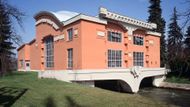 Výtvarné napětí Vodní elektrárna Háj (součást obce Třeština, místní části Mohelnice; okres Šumperk) Bohuslav Fuchs a Josef Štěpánek, 1921-1922  Starodávný mlýn s pilou při umělém náhonu na levém břehu řeky Moravy patřil po generace rodině Plhákových. Hubert Plhák, osvícený hospodář a průkopník nových výrobních postupů a technologií, se v roce 1894 rozhodl využít pro svoje podnikání elektromotory napájené ze dvou dynam poháněných vodním kolem. Po různých experimentech založil v roce 1901 „První moravskou zemědělskou elektrárnu s.r.o. v Hajském mlýně u Mohelnice". Tato soukromá elektrárna, nejstarší na území Rakousko-Uherska, poháněla výrobní zařízení a s velkými ztrátami dodávala proud i do místní sítě. Nový hospodář, syn Karel Plhák, se rozhodl postavit na místě starého mlýna novostavbu vodní elektrárny. Její projekt dodali v roce 1921 na doporučení Jana Kotěry čerství absolventi jeho Mistrovské školy architektury na Akademii výtvarných umění v Praze Bohuslav Fuchs a Josef Štěpánek. Po čtrnácti měsících byla elektrárna dokončena a v roce 1922 uvedena do provozu.