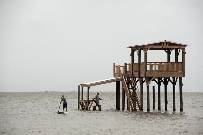 Blake Noblin paddles back to shore after helping his father Jeff Noblin gather boards from a neighbor's pier on East Beach as Hurricane Isaac approaches Ocean Springs, Mississippi, August 28, 2012. REUTERS/Michael Spooneybarger (UNITED STATES - Tags: ENVIRONMENT DISASTER) Published: Srp. 28, 2012, 8:53 odp.