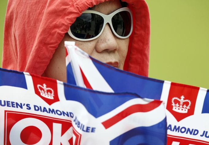 A woman holds flags as spectators line Parliament Square to see the Queen in London June 5, 2012. Four days of nationwide celebrations during which millions of people have turned out to mark the Queen's Diamond Jubilee conclude on Tuesday with a church service and carriage procession through central London. REUTERS/Kevin Coombs (BRITAIN - Tags: SOCIETY ROYALS) Published: Čer. 5, 2012, 1:38 odp.