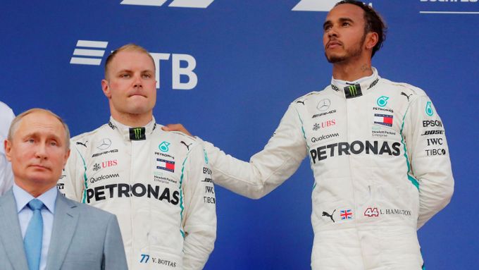 Smutný Valtteri Bottas a vítězný Lewis Hamiotn na stupních vítězů. Před nimi stojí s kamennou tváří ruský prezident Vladimir Putin.