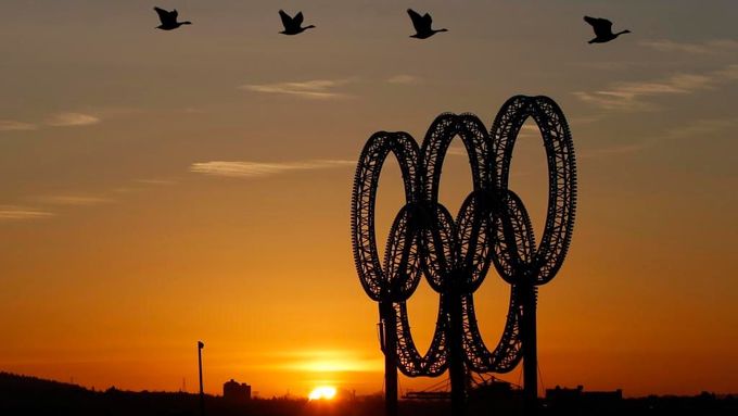 Husy přelétávají za rozbřesku nad olympijskými kruhy ve Vancouveru, kde se konala zimní olympiáda.