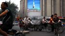 Commuters ride bicycles and electric bikes as they pass a large screen displaying pictures of China's recent spacecraft launch in the centre of Beijing June 18, 2012. A Chinese spacecraft carried out a manned docking with an experimental space module on Monday, the latest milestone in China's ambitious effort to build a space station. REUTERS/David Gray (CHINA - Tags: SOCIETY SCIENCE TECHNOLOGY) Published: Čer. 18, 2012, 10:17 dop.