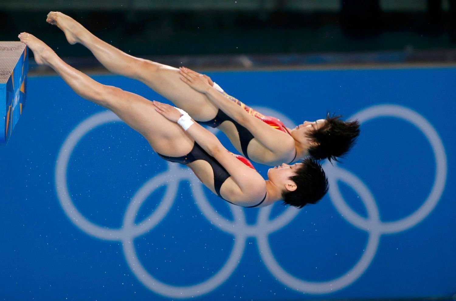 Čínské synchonizované skokanky Ruolin Čenová a Hao Wangová skáčou vítězný skok z 10 metrů na OH 2012 v Londýně.