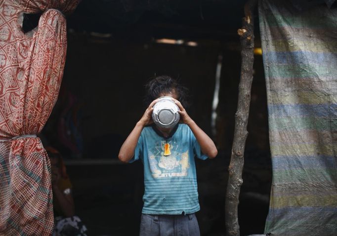 Shivani Choudhary, 7, a street performer drinks tea outside her hut at a slum on the bank of Manahara River before leaving to perform on the streets of Kathmandu August 15, 2012. Shivani and her brothers Drumpal and Gchan, who came to Kathmandu from India 5 years ago, earn their living by performing tricks on the streets of Kathmandu. According to Drumpal, Shivani's older brother, they earn around $10 a day by performing tricks, which is not enough to feed their 10-member family living together in a small hut without a proper toilet or any basic needs. REUTERS/Navesh Chitrakar (NEPAL - Tags: SOCIETY IMMIGRATION POVERTY) Published: Srp. 15, 2012, 3:59 odp.