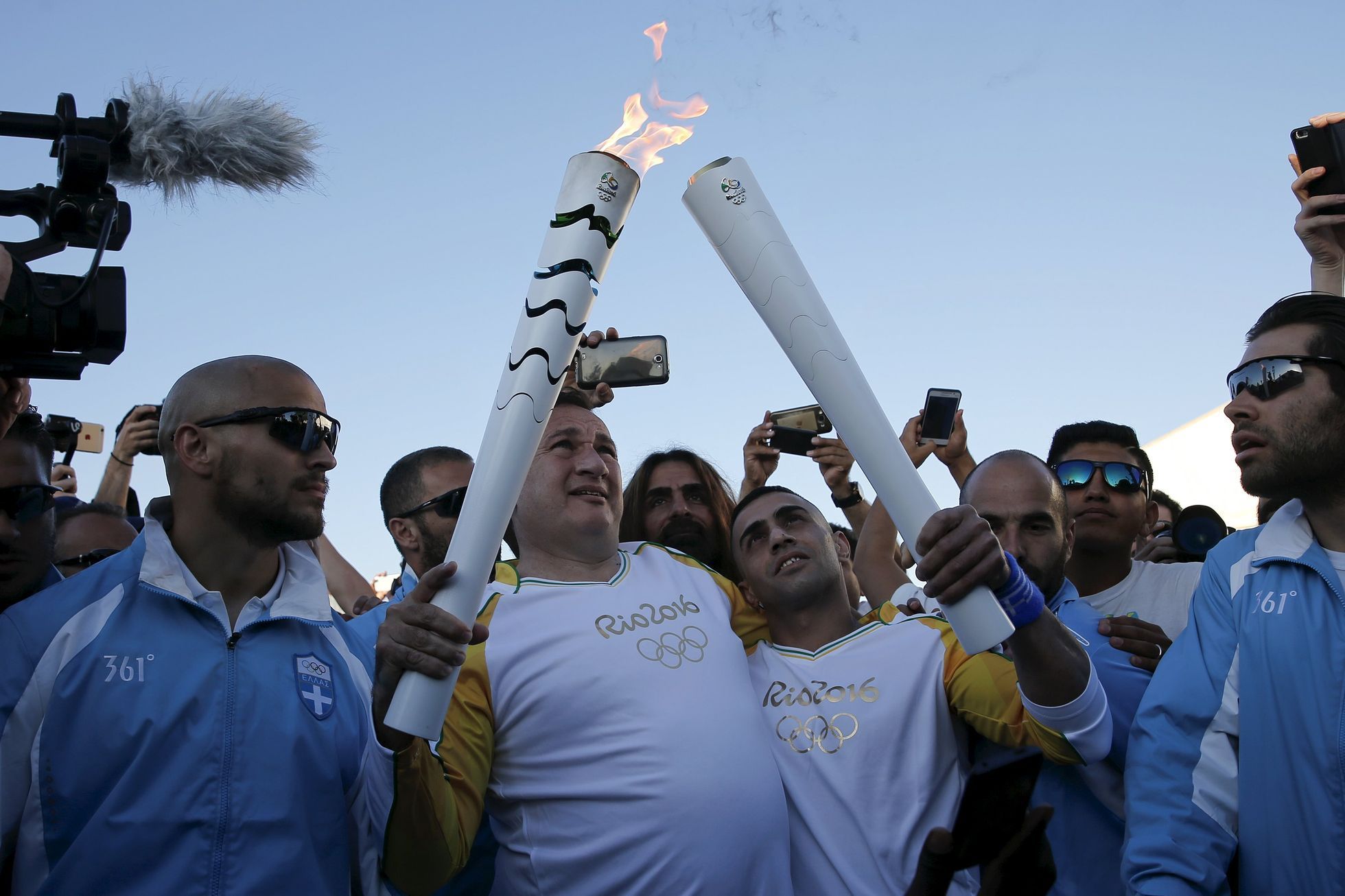 Ibrahim Hussejn (vpravo s olympijskou pochodní) přebírá olympijský oheň.