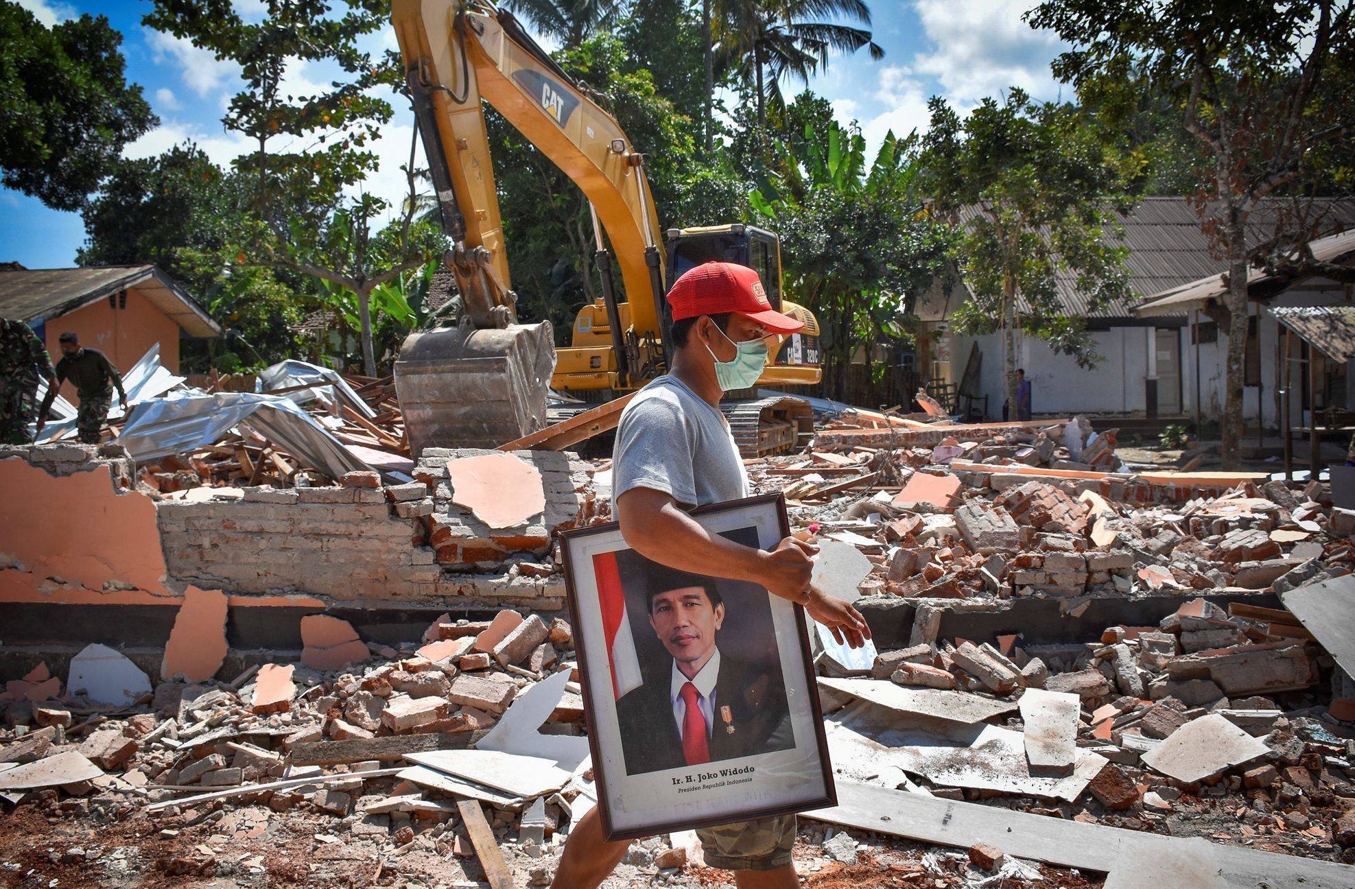 Indonésan odnáší ze zničené školy na Lomboku portrét tamního prezidenta.