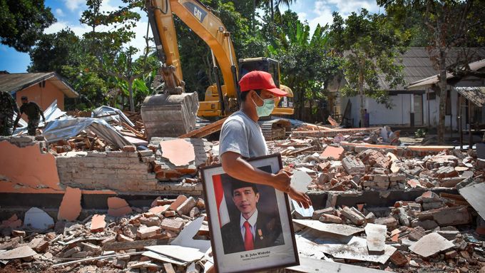 Indonésan odnáší ze zničené školy na Lomboku portrét tamního prezidenta.