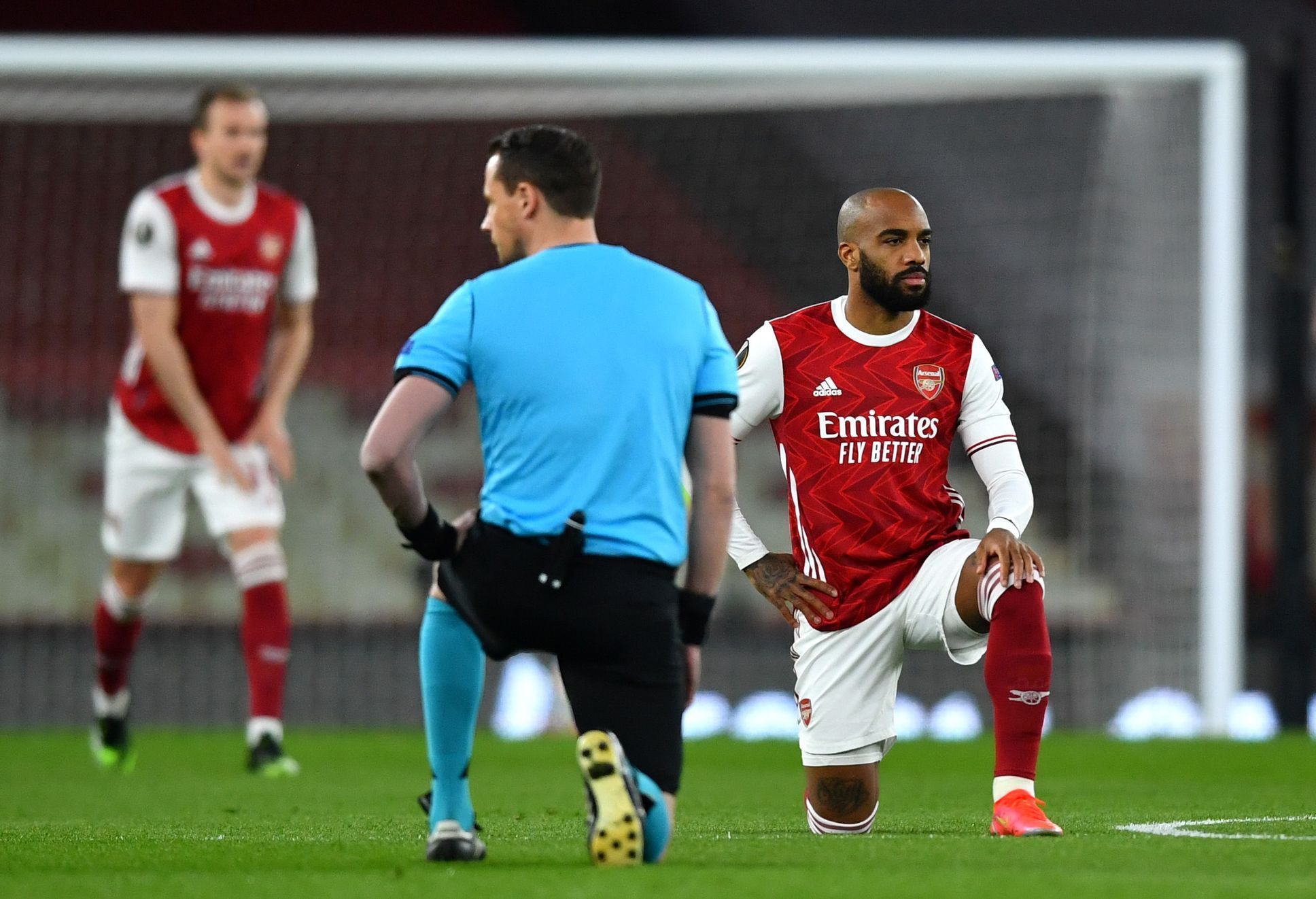 Rozhodčí a hráč Arsenalu Alexandre Lacazette klečí před čtvrtfinále EL Arsenal - Slavia