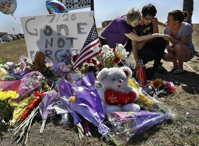 Isaac Pacheco (C) is comforted after leaving a birthday card for his friend Alex Sullivan, who was killed in the Denver-area movie killings, at a memorial site for victims behind the theater where a gunman opened fire on moviegoers in Aurora, Colorado July 21, 2012. A day after a gunman opened fire at a packed midnight showing of the new "Batman" film in a Denver suburb, killing 12 people and wounding 59 more, police on Saturday prepared to neutralize explosives in the suspect's booby-trapped apartment. The suspect, identified by police as James Eagan Holmes, 24, booby-trapped his Aurora apartment with sophisticated explosives, creating a hazard for law-enforcement and bomb squad officers who swarmed to the scene. REUTERS/Shannon Stapleton (UNITED STATES - Tags: ENTERTAINMENT CRIME LAW DISASTER SOCIETY TPX IMAGES OF THE DAY) Published: Čec. 21, 2012, 9:28 odp.