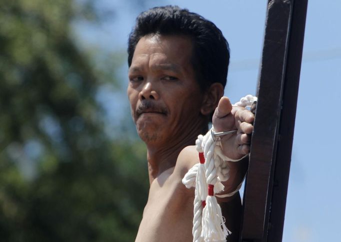 Renato Cunanan, 48, who portrays Jesus Christ, looks at the nail in his palm on a wooden cross during a Good Friday crucifixion re-enactment in San Juan village, Pampanga province, north of Manila March 29, 2013. The Roman Catholic church frowns on the gory spectacle held in the Philippine village of Cutud every Good Friday but that does nothing to deter the faithful from emulating the suffering of Christ and taking a painful route to penitents. Holy Week is celebrated in many Christian traditions during the week before Easter. REUTERS/Romeo Ranoco (PHILIPPINES - Tags: RELIGION SOCIETY) Published: Bře. 29, 2013, 4:44 dop.