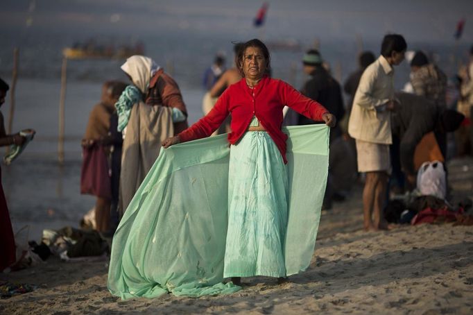 A Hindu woman gets dressed after taking a dip in the waters of the holy Ganges river ahead of the "Kumbh Mela" (Pitcher Festival), in the northern Indian city of Allahabad January 11, 2013. During the festival, Hindus take part in a religious gathering on the banks of the river Ganges. "Kumbh Mela" will return to Allahabad in 12 years. REUTERS/Ahmad Masood (INDIA - Tags: RELIGION) Published: Led. 11, 2013, 10:15 dop.