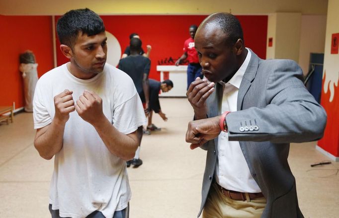 Former Belgian boxing champion Bea Diallo gives instructions to unemployed Mohamed Sammar (L) during a "Fit for a job" boxing class in Brussels July 5, 2013. Sammar, 27, has been looking for a job in the construction sector for 2 years. "Fit for a job" is the initiative of former Belgian boxing champion Bea Diallo, whose goal was to restore the confidence of unemployed people and help them find a job through their participation in sports. Picture taken July 5, 2013. REUTERS/Francois Lenoir (BELGIUM - Tags: SPORT BOXING SOCIETY BUSINESS EMPLOYMENT) Published: Čec. 5, 2013, 4:50 odp.