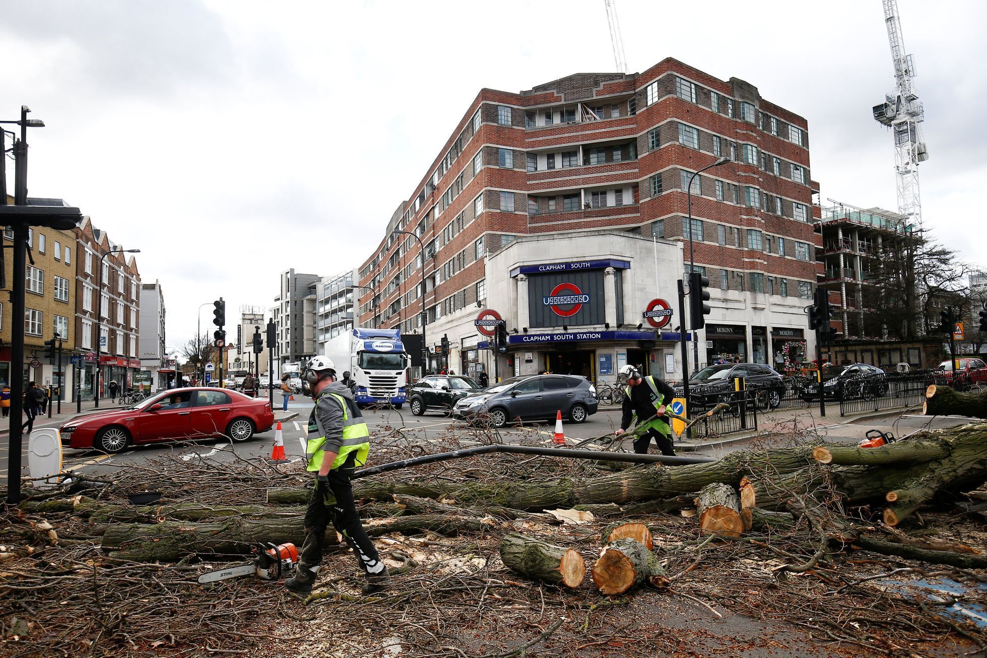 Workers remove a tree lying across a road after it was blown over by high winds, in London