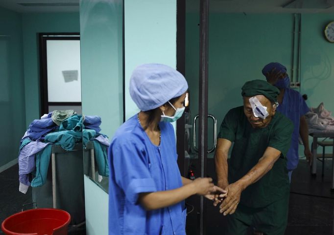 A patient is helped by a nurse after undergoing a surgery to remove his cataract at the Tilganga Eye Center in Kathmandu April 25, 2012. About 150,000 of Nepal's 26.6 million people are estimated to be blind in both eyes, most of them with cataracts. Picture taken April 25, 2012. REUTERS/Navesh Chitrakar (NEPAL - Tags: HEALTH SOCIETY POVERTY) Published: Kvě. 2, 2012, 4:38 dop.