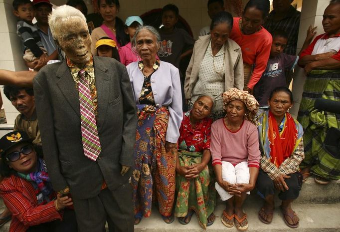 Family members hold up a mummy before giving it new clothes in a ritual in the Toraja district of Indonesia's South Sulawesi Province, August 23, 2012. The ritual, called Ma'nene, involves changing the clothes of mummified ancestors every three years to honor love for the deceased. Locals believe dead family members are still with them, even if they died hundreds of years ago, a family spokesman said. Picture taken August 23, 2012. REUTERS/Yusuf Ahmad (INDONESIA - Tags: SOCIETY RELIGION) Published: Srp. 24, 2012, 12:57 odp.