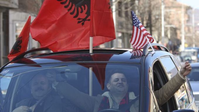 Řidič v Mitrovici oslavuje s kosovskou a americkou vlajkou.