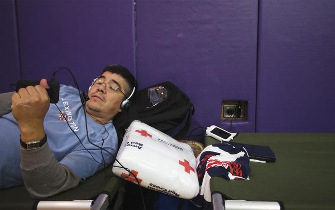 A man watches a movie on his phone at a Red Cross shelter in Hampton Bays, New York October 29, 2012. Hurricane Sandy, the monster storm bearing down on the East Coast, strengthened on Monday after hundreds of thousands moved to higher ground, public transport shut down and the stock market suffered its first weather-related closure in 27 years. REUTERS/Lucas Jackson (UNITED STATES - Tags: ENVIRONMENT DISASTER) Published: Říj. 29, 2012, 11:32 odp.