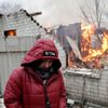 Ukrajinka stojí vedle svého domu, který byl poškozen ostřelováním v Doněcku a zachvátil ho požár.
