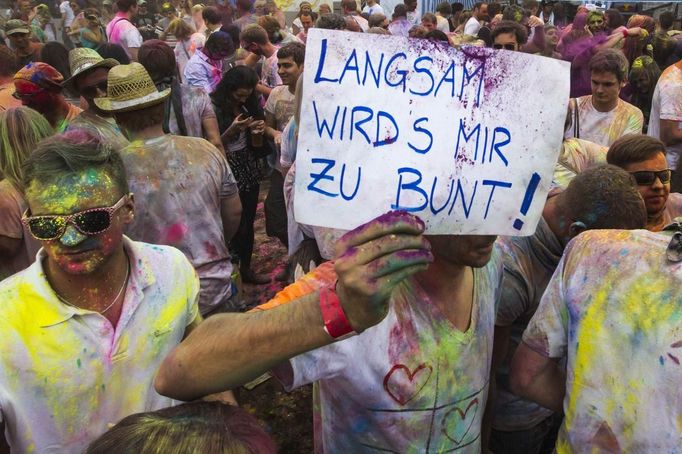 A man holds up a banner during the Holi festival in Berlin, July 29, 2012. Holi, also known as the festival of colours, is a festival celebrated in India and other Hindu countries that in its original form heralds the beginning of spring. The Berlin event brought Indian Djs, acrobatics and dance to the German capital. The message reads "Slowly it is getting too colourful". REUTERS/Thomas Peter (GERMANY - Tags: SOCIETY) Published: Čec. 29, 2012, 3:29 odp.