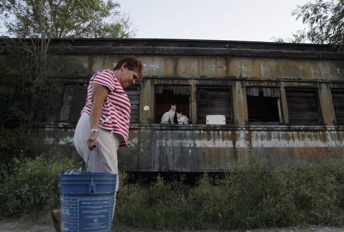 Maria Guadalupe carries a bucket with water while walking outside a train carriage she calls home in Cadereyta on the outskirts of Monterrey August 8, 2012. Maria Guadalupe, her eight other family members and their pets have been living in the abandoned carriage next to a train track for the last 15 years. Maria Guadalupe and her husband moved from Tamaulipas to Cadereyta after one of their sons was killed on the street by a stray bullet. The family moved into the carriage, which was empty after having been occupied by a vagabond, after living for the first five years in a rented room after arriving in Cadereyta. Picture taken August 8, 2012. REUTERS/Daniel Becerril (MEXICO - Tags: SOCIETY) Published: Srp. 11, 2012, 1:59 dop.