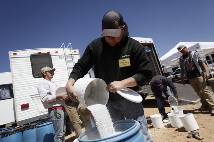 Workers prepare buckets of aluminum oxide mixed with ammonium nitrate to use for targets during the Big Sandy Shoot in Mohave County, Arizona March 23, 2013. The Big Sandy Shoot is the largest organized machine gun shoot in the United States attended by shooters from around the country. Vintage and replica style machine guns and cannons are some of the weapons displayed during the event. REUTERS/Joshua Lott (UNITED STATES - Tags: SOCIETY) Published: Bře. 25, 2013, 3:35 odp.