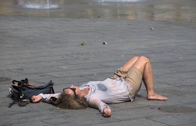 Žena odpočívá u fontány v centru Bruselu.