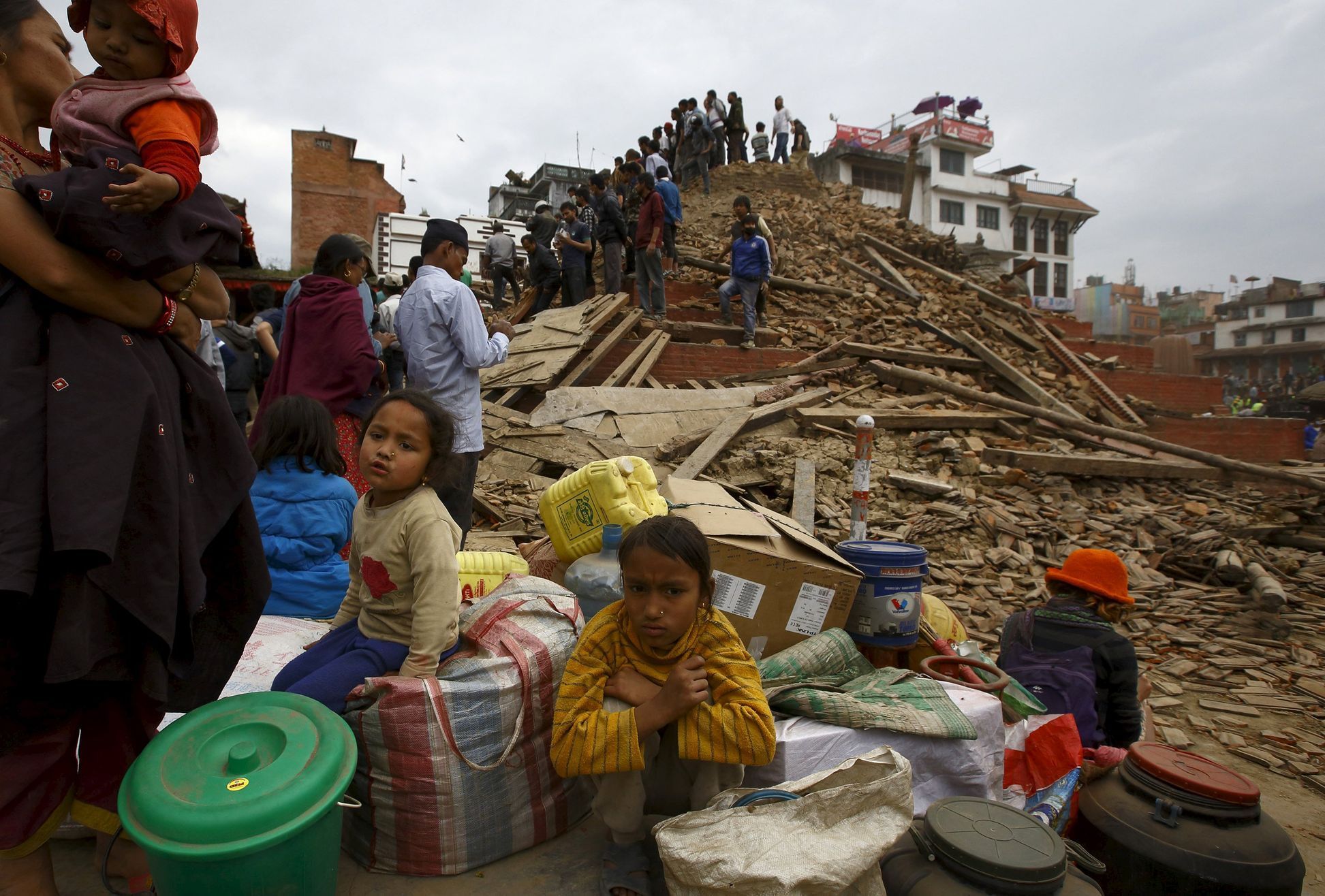 People sit with their belongings outside a damaged temple in Bashantapur Durbar Square after a major earthquake hit Kathmandu
