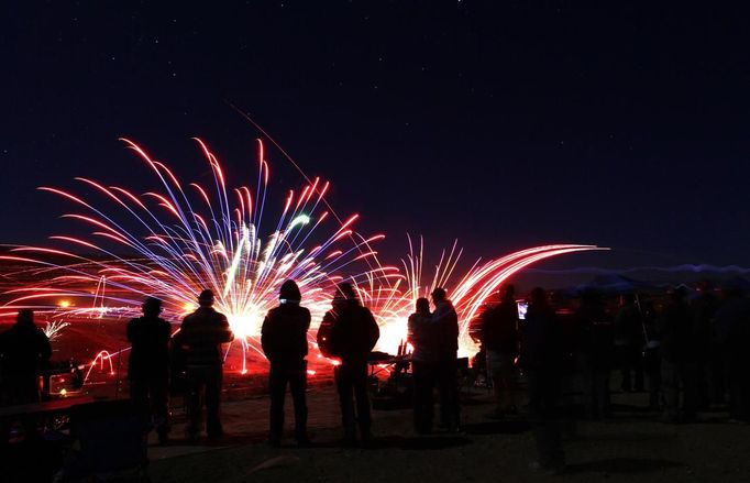 Spectators watch as fireworks used as targets are ignited by tracers from shooters firing their guns during the Big Sandy Shoot in Mohave County, Arizona March 23, 2013. The Big Sandy Shoot is the largest organized machine gun shoot in the United States attended by shooters from around the country. Vintage and replica style machine guns and cannons are some of the weapons displayed during the event. Picture taken March 22, 2013. REUTERS/Joshua Lott (UNITED STATES - Tags: SOCIETY) Published: Bře. 25, 2013, 3:35 odp.