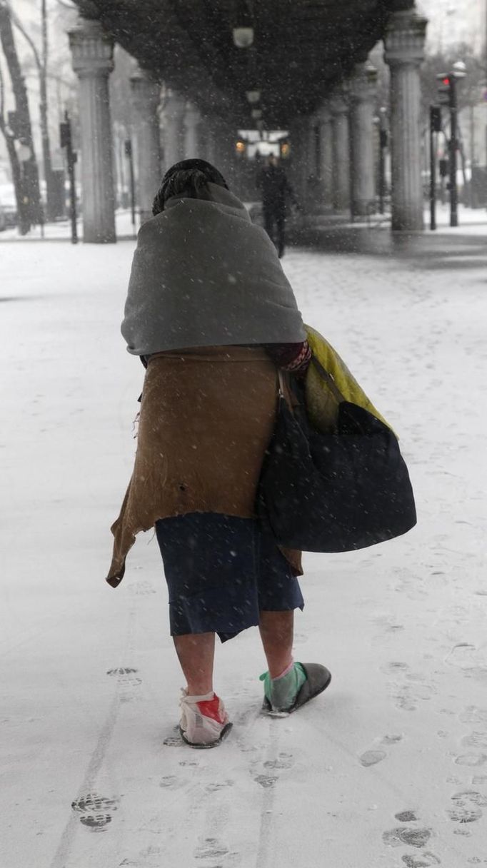 A homeless woman, her feet wrapped in plastic, walks in the snow in Paris March 12, 2013 as winter weather with snow and freezing temperatures returns to northern France. REUTERS/John Schults (FRANCE - Tags: ENVIRONMENT SOCIETY POVERTY) Published: Bře. 12, 2013, 1:03 odp.