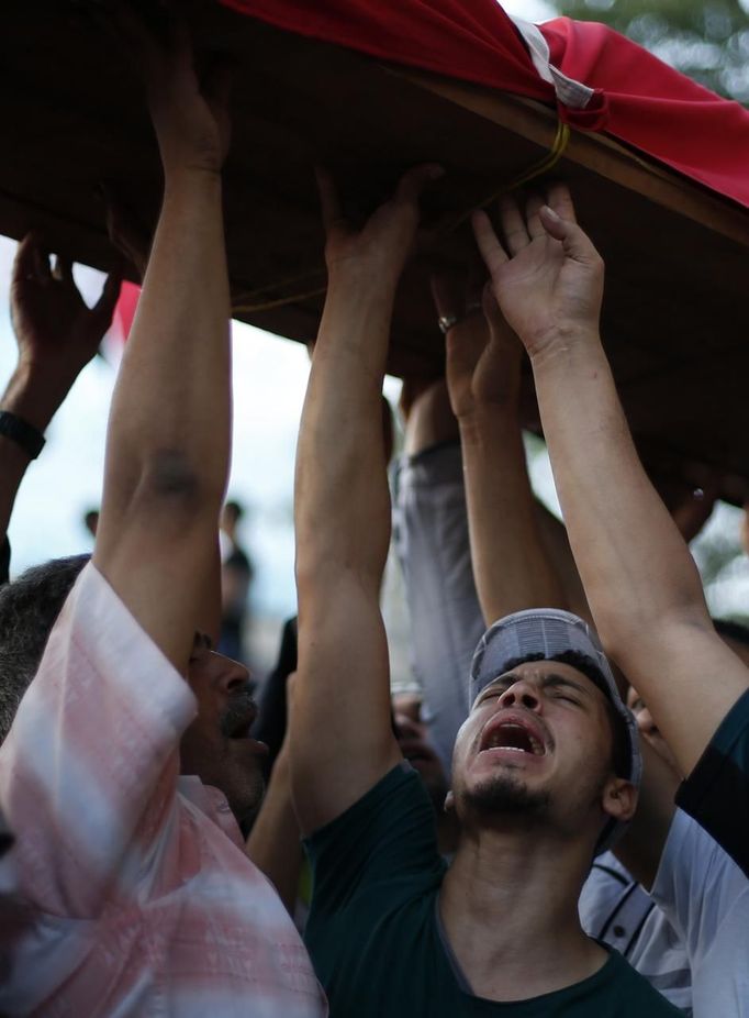 A man reacts as the flag draped body of a victim from this morning's fighting outside Cairo University is carried through protesters, who are against Egyptian President Mohamed Mursi, gathering in Tahrir Square in Cairo July 3, 2013. The Egyptian president's national security adviser said on Wednesday that a "military coup" was under way and army and police violence was expected to remove pro-Mursi demonstrators. REUTERS/Suhaib Salem (EGYPT - Tags: POLITICS CIVIL UNREST) Published: Čec. 3, 2013, 6:36 odp.