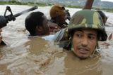 Voják z jednotek Spojených národů pomáhá obyvatelům města Gonaives přebrodit řeku.