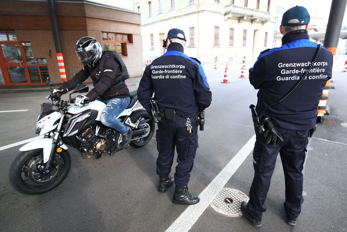 Motorkář projíždí kolem policejní hlídky na švýcarsko-italském hraničním řechodu v Chiassu.