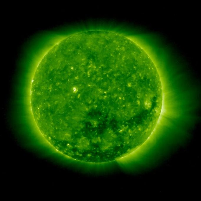 A coronal hole, the dark spot beginning just below the sun's center and extending to the right, is shown opening up in this image by NASA satellite STEREO. The NASA satellite SABER has detected a periodic "breathing" response in the Earth's upper atmosphere in response to never before observed regular coronal hole openings on the sun's surface. The coronal holes release high-powered solar winds that disturb the upper atmosphere of Earth and force it to emit energy to maintain the earth's radiation budget. Image credit: NASA/STEREO