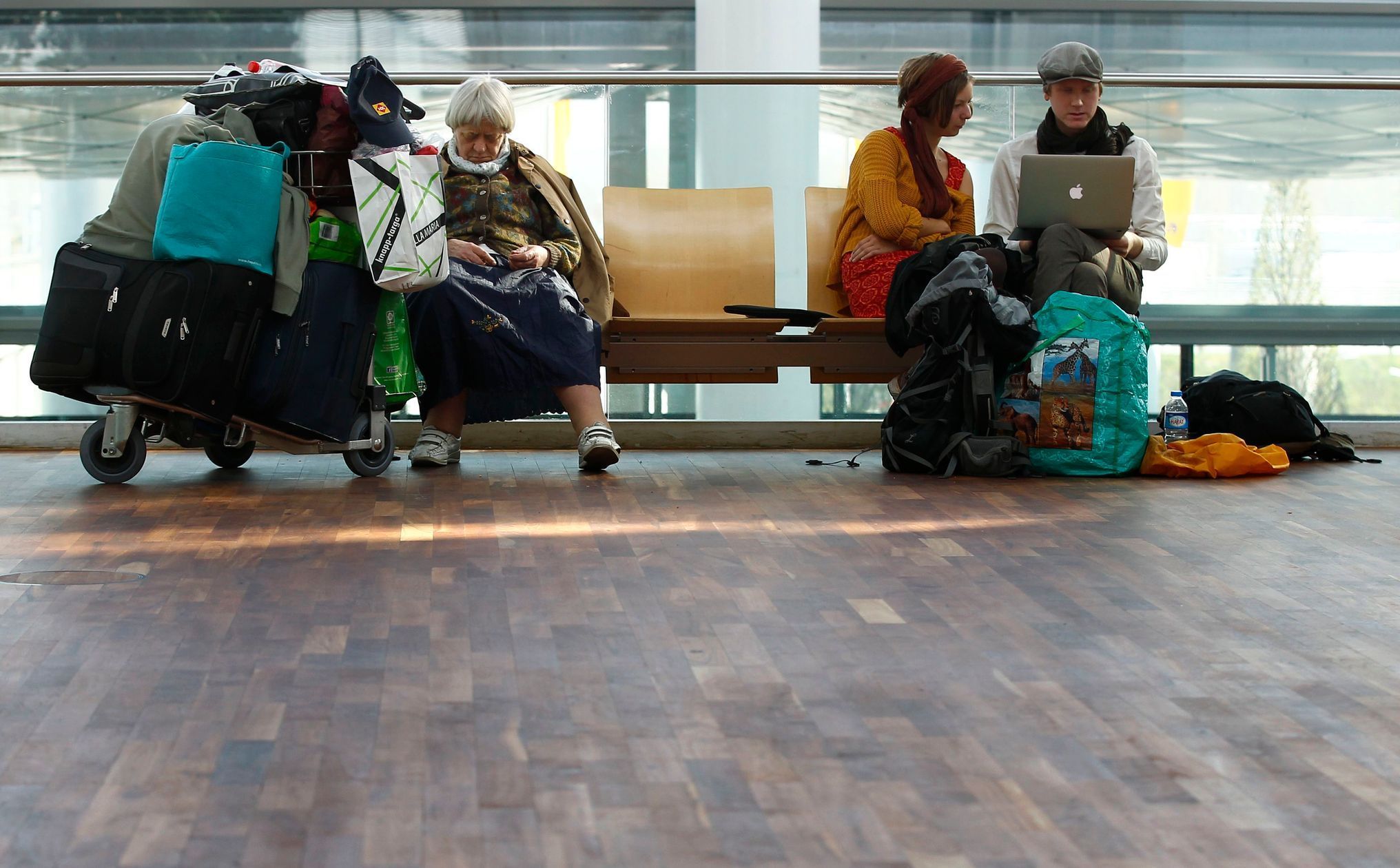 Passenger sleeps as others use laptop while waiting for flights with Lufthansa at Munich's airport