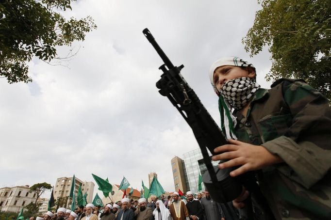 A boy with a toy rifle stands near people taking part in a protest, organized by a Muslim Brotherhood group, in solidarity with the Palestinians in Gaza, in front of the United Nations headquarters in Beirut November 18, 2012. Fighting between Israel and Palestinian militants continued for a fifth straight day, with Hamas firing two rockets at Tel Aviv, but Israel's Iron Dome air shield shot them down. Israel, meanwhile, continued to strike at militant targets in Gaza. REUTERS/Jamal Saidi (LEBANON - Tags: CIVIL UNREST POLITICS MILITARY) Published: Lis. 18, 2012, 1:29 odp.