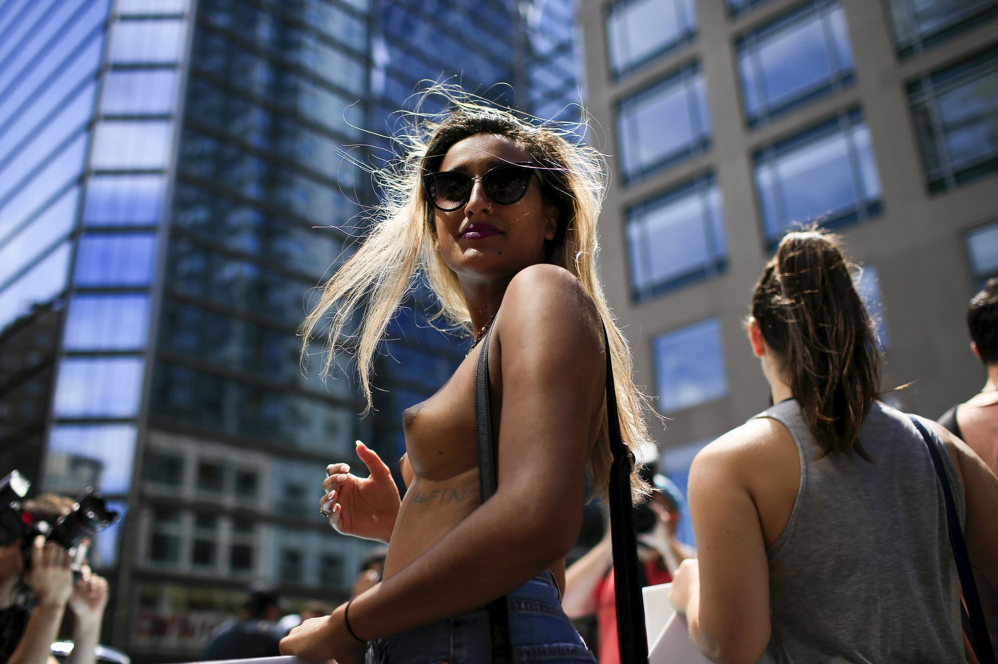 A woman awaits the start of a topless march in New York.