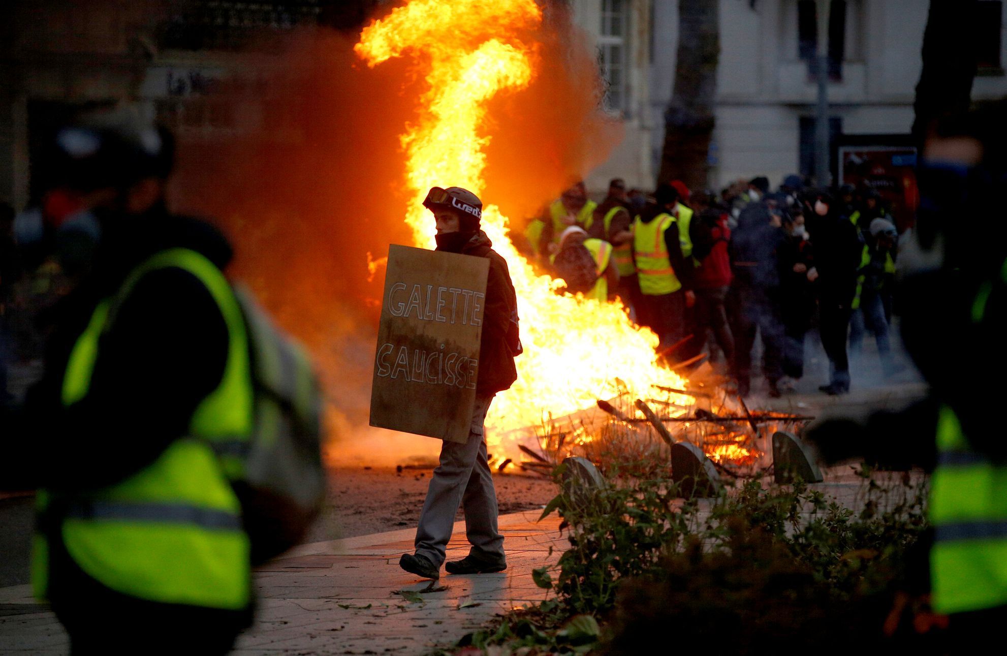 Protestující prochází kolem hořící barikády během demonstrace hnutí žlutých vest v Nantes.