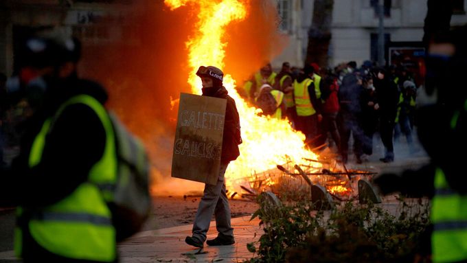 Protestující prochází kolem hořící barikády během demonstrace hnutí žlutých vest v Nantes.
