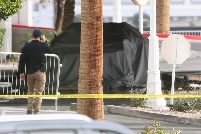 A law enforcement officer walks near the remains of a covered Tesla Cybertruck that burned at the entrance of Trump Tower, in Las Vegas, Nevada, U.S. January 1, 2025.  RE