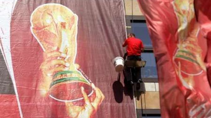 Dělník upevňuje na jednu z berlínských budov obří transparent připomínající světový fotbalový šampionát.