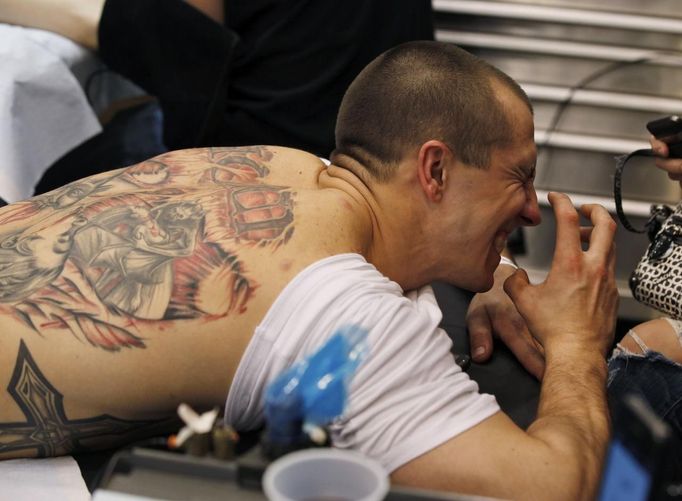 Ron Raucci from Norfolk, Virginia, reacts to the needle while getting his Captain America tattoo at the Hampton Roads Tattoo Festival in Virginia March 2, 2012. Raucci, who serves in the U.S. Navy, grew up reading Marvel comic books and has a leg tattoo collage featuring Captain America and Wolverine, his next planned tattoo will feature The Hulk. Picture taken March 2, 2012. REUTERS/Larry Downing (UNITED STATES - Tags: SOCIETY) ATTENTION EDITORS PICTURE 07 OF 31 FOR PACKAGE 'ADDICTED TO THE NEEDLE' TO FIND ALL PICTURES SEARCH 'ADDICTED NEEDLE' Published: Čer. 29, 2012, 12:59 odp.