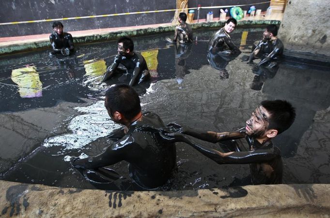 People take a dip in a black mud pool at a tourist resort to escape the summer heat in Daying county of Suining, Sichuan province August 19, 2012. Picture taken August 19, 2012. REUTERS/Stringer (CHINA - Tags: ENTERTAINMENT ENVIRONMENT TRAVEL TPX IMAGES OF THE DAY) CHINA OUT. NO COMMERCIAL OR EDITORIAL SALES IN CHINA Published: Srp. 20, 2012, 5:53 dop.