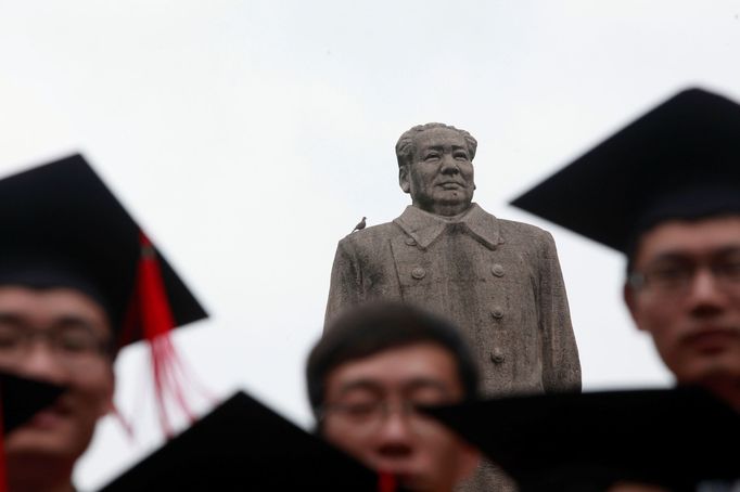 Absolventi univerzity Fu-tan v Šanghaji pózují během promocí se sochou Mao Ce-tunga.