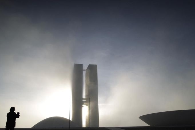 A man stands near the National Congress building, designed by Brazilian architect Oscar Niemeyer, in the Ministries Esplanade in Brasilia December 6, 2012. Niemeyer, a towering patriarch of modern architecture who shaped the look of modern Brazil and whose inventive, curved designs left their mark on cities worldwide, died late on Wednesday. He was 104. Niemeyer had been battling kidney and stomach ailments in a Rio de Janeiro hospital since early November. His death was the result of a lung infection developed this week, the hospital said, little more than a week before he would have turned 105. REUTERS/Ueslei Marcelino (BRAZIL - Tags: POLITICS SOCIETY CITYSCAPE) Published: Pro. 6, 2012, 11:04 dop.