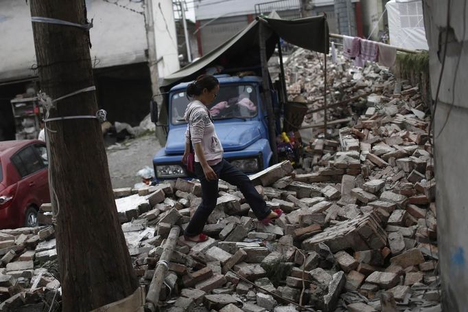 A woman walks among debris after Saturday's earthquake in Lushan county, April 22, 2013. Rescuers struggled to reach a remote, rural corner of southwestern China on Sunday as the toll of the dead and missing from the country's worst earthquake in three years climbed to 208 with almost 1,000 serious injuries. The 6.6 magnitude quake struck in Lushan county, near the city of Ya'an in the southwestern province of Sichuan, close to where a devastating 7.9 quake hit in May 2008, killing 70,000. REUTERS/Aly Song (CHINA - Tags: DISASTER SOCIETY) Published: Dub. 22, 2013, 3:50 dop.