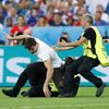 Stewards tackle a fan who invades the pitch
