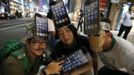 Men wearing cardboard hats, depicting Apple's new iPhone 5, pose for photos as they wait for the release of the phone near Apple Store Ginza in Tokyo September 20, 2012. REUTERS/Toru Hanai (JAPAN - Tags: BUSINESS SOCIETY TELECOMS TPX IMAGES OF THE DAY) Published: Zář. 20, 2012, 11:59 dop.