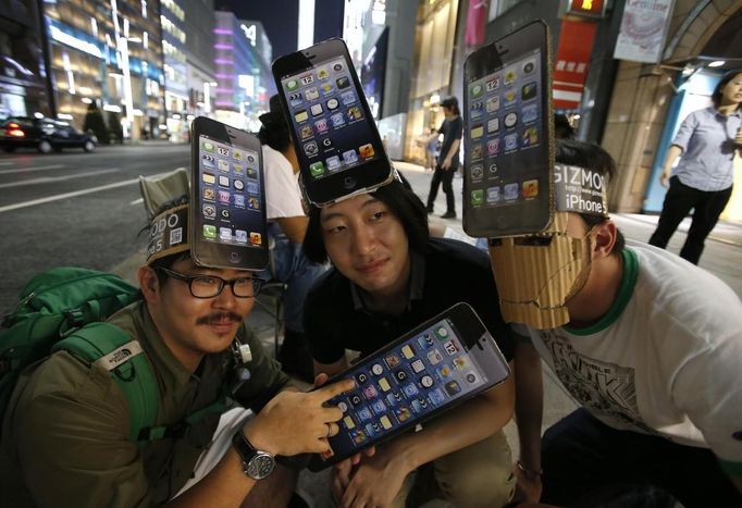 Men wearing cardboard hats, depicting Apple's new iPhone 5, pose for photos as they wait for the release of the phone near Apple Store Ginza in Tokyo September 20, 2012. REUTERS/Toru Hanai (JAPAN - Tags: BUSINESS SOCIETY TELECOMS TPX IMAGES OF THE DAY) Published: Zář. 20, 2012, 11:59 dop.